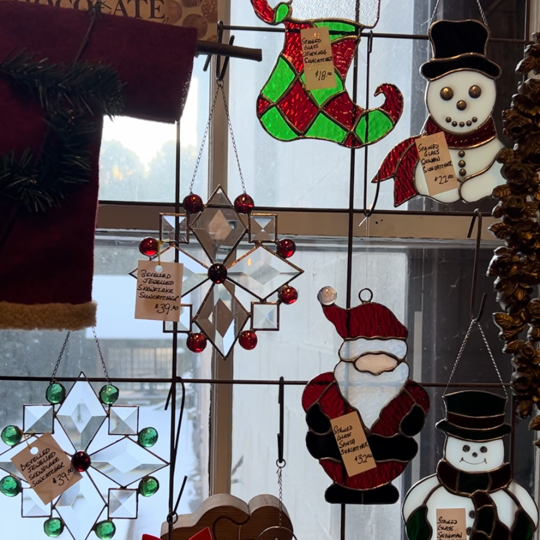 a bunch of stained glass Christmas hangers hanging against a window 