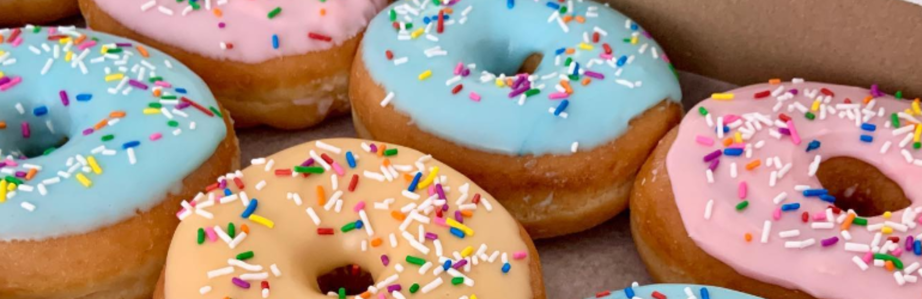 Donuts with pink, blue and orange icing and rainbow sprinkles 