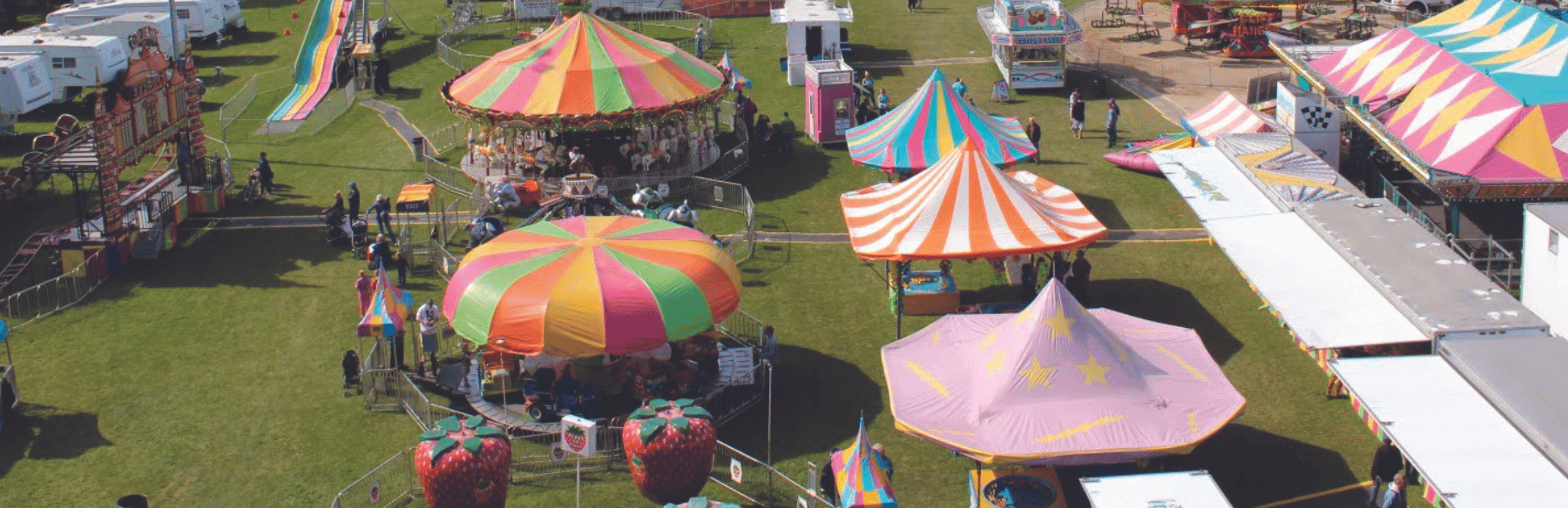 A bunch of fair rides and events with colourful tents 