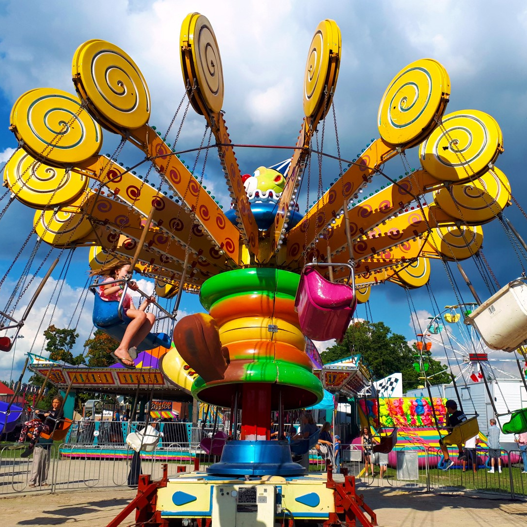 An image of the giant swing ride at the Acton Fall Fair. There is a little girl sitting in one of the swings