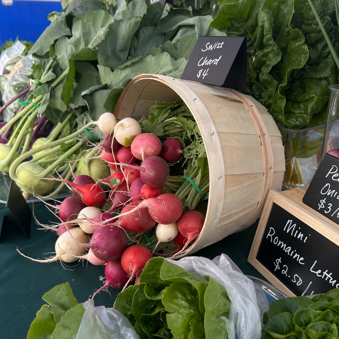 A table of different beets, lettuce and other greens at the farmers market