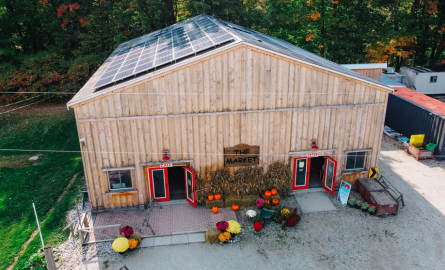 a brown barn made of wood. There is a sign on it that says "The Market" it has two sets of red doors on each side of the front of the barn